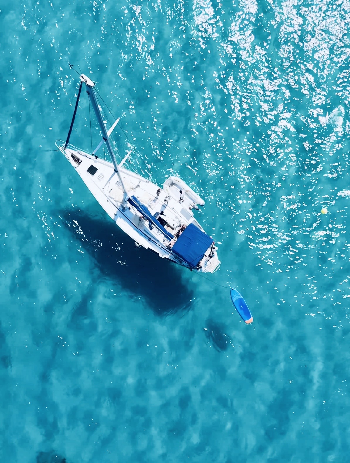 Vista aérea del velero y una tabla de paddle en agua turquesa