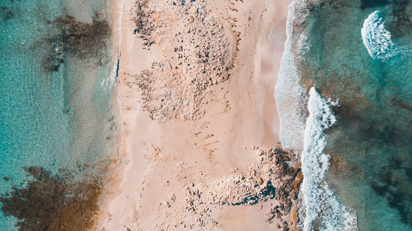 Vista aérea de arena, roca y agua clara en Espalmador