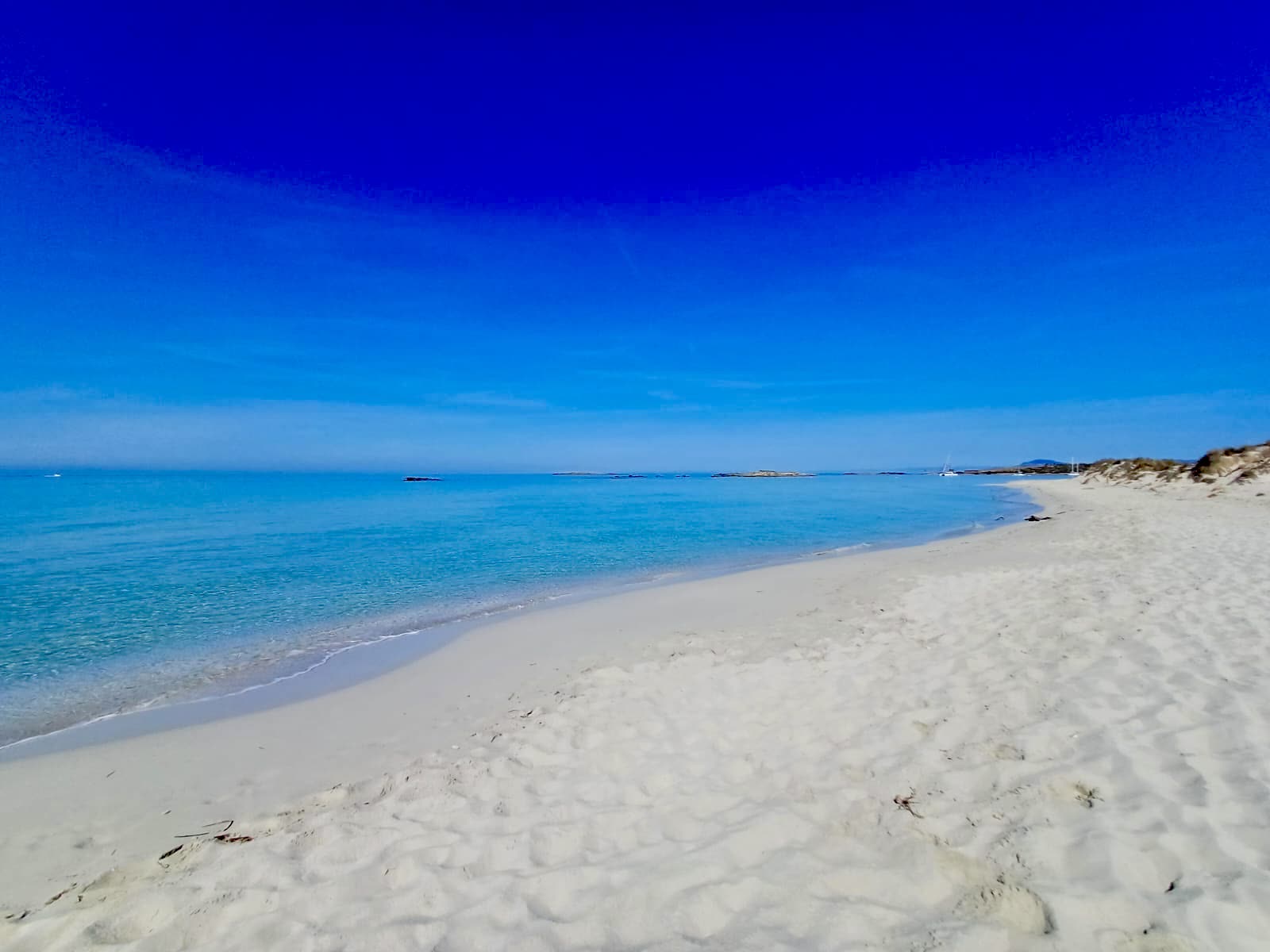 White sand and turquoise water on a Formentera beach reached by boat